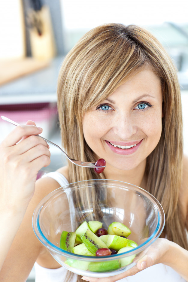 ritratto-di-una-donna-radiosa-che-mangia-una-macedonia-nella-cucina_13339-81077